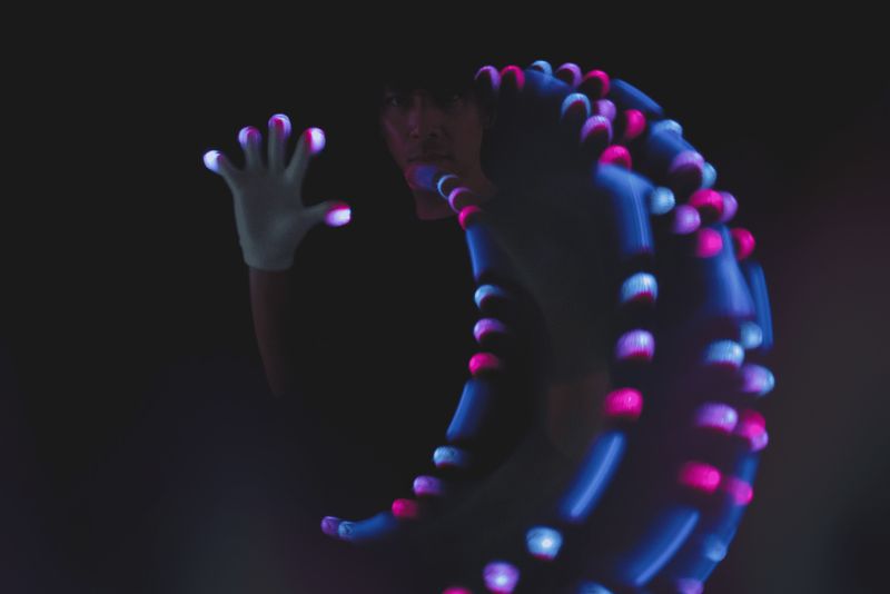 Glover reaching toward the camera with a glowing light-trail loop behind their hand