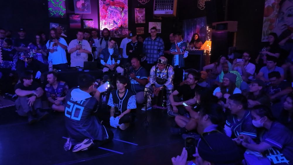 A glover performing kneeling in front of a small seated crowd at an event