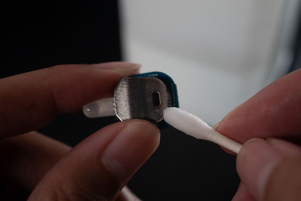 Macro close-up of a cotton swab cleaning a microlight's battery contact points